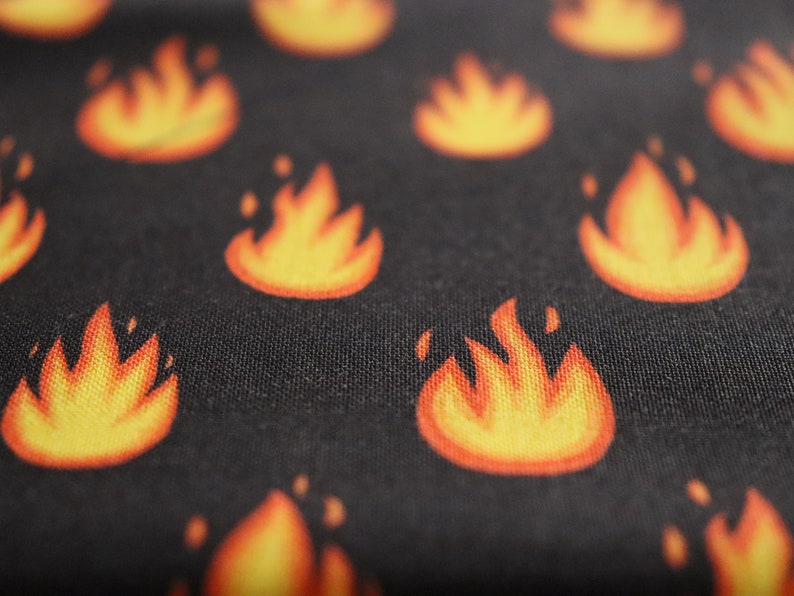 May include: Black fabric with a repeating pattern of orange flames.