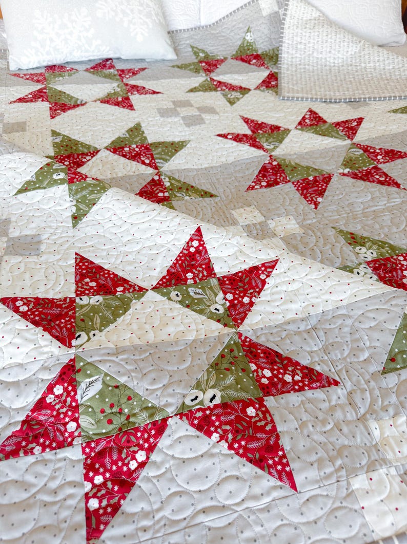 May include: A quilted throw blanket with a star pattern in shades of red, green, and white. The blanket is made with a variety of fabrics and has a subtle texture.