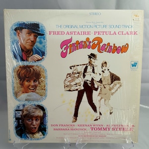 Peut inclure: Un album vinyle vintage pour le film "Finian's Rainbow". La pochette de l'album présente des images de Fred Astaire et Petula Clark, avec le titre dans une police colorée et stylisée. L'album est scellé dans du plastique.