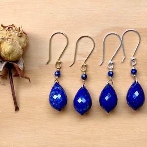 May include: Four pairs of dangle earrings with teardrop-shaped lapis lazuli stones. Two pairs have gold hooks and two pairs have silver hooks.