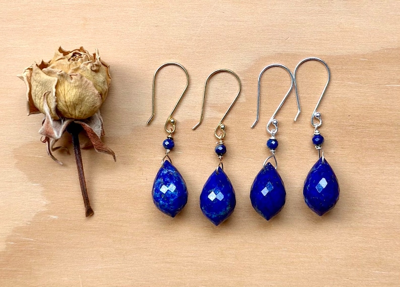 May include: Four pairs of dangle earrings with teardrop-shaped lapis lazuli stones. Two pairs have gold hooks and two pairs have silver hooks.