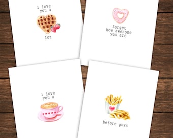 May include: Four greeting cards with food-themed illustrations and text. The first card features a heart-shaped waffle with strawberries and the text "i love you a lot". The second card features a heart-shaped donut with pink frosting and the text "forget how awesome you are". The third card features a cup of coffee with a heart design in the foam and the text "i love you a". The fourth card features a box of french fries with a heart on the box and the text "before guys".