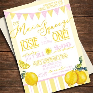 May include: A yellow and pink birthday party invitation with a lemon theme. The invitation says "Our Main Squeeze is turning One!" with a date of Saturday, July 21st at 2:00 in the afternoon. The invitation also includes the address for Josie's Lemonade Stand and an RSVP number.