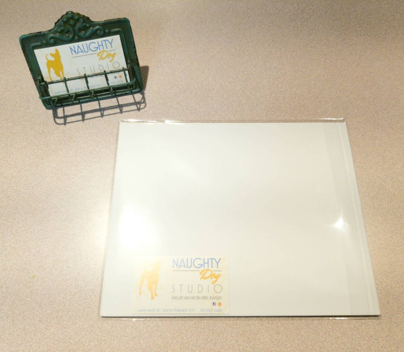 May include: White card with a green and yellow logo that says "NAUGHTY Dog STUDIO" with a small dog silhouette. The card is on a white surface.