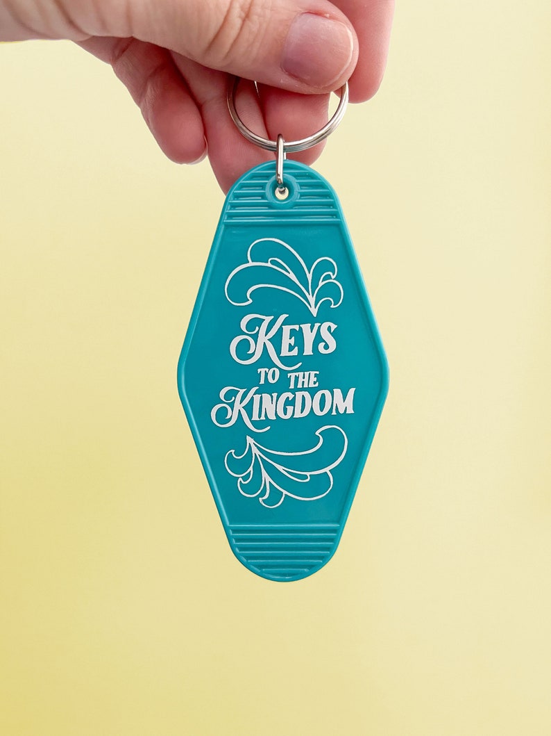 K&ouml;nnte beinhalten: Ein t&uuml;rkisfarbener Motel-Schl&uuml;sselanh&auml;nger mit dem Text "Keys to the Kingdom" in wei&szlig;en Buchstaben. Der Schl&uuml;sselanh&auml;nger hat einen silbernen Schl&uuml;sselring.