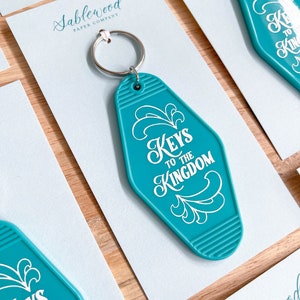 K&ouml;nnte beinhalten: T&uuml;rschild-Schl&uuml;sselanh&auml;nger in T&uuml;rkisblau mit wei&szlig;er Aufschrift "Keys to the Kingdom".
