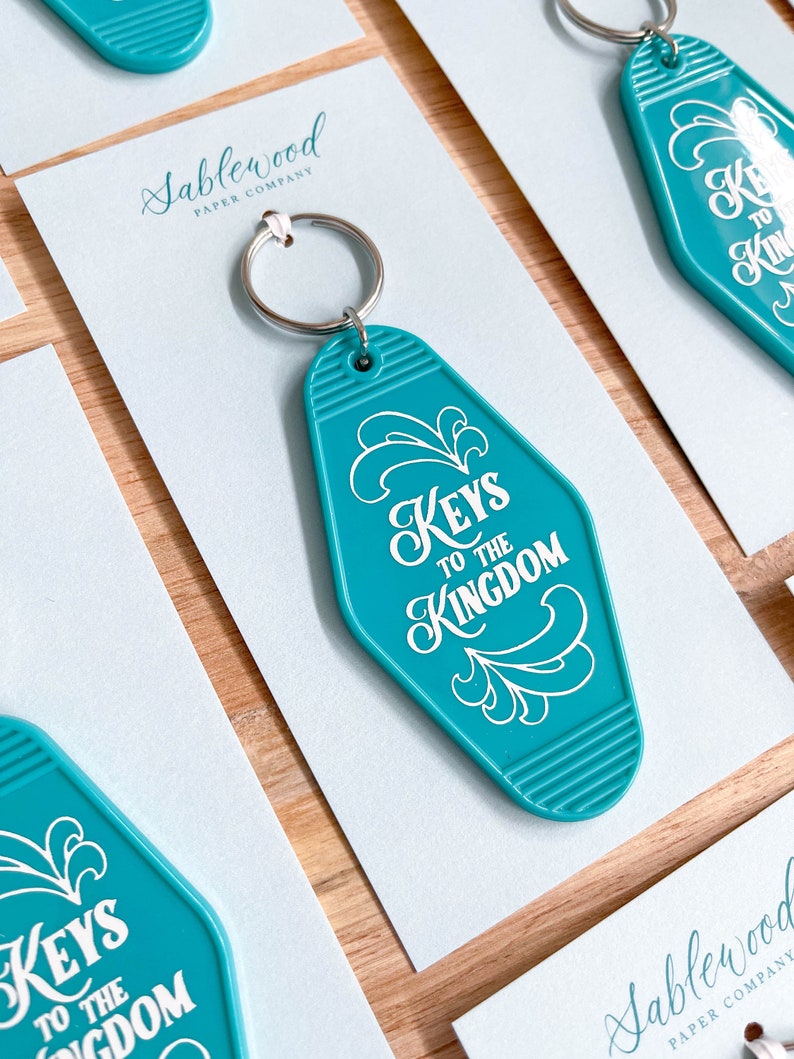 K&ouml;nnte beinhalten: T&uuml;rschild-Schl&uuml;sselanh&auml;nger in T&uuml;rkisblau mit wei&szlig;er Aufschrift "Keys to the Kingdom".