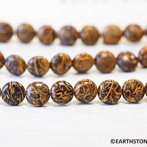 May include: A strand of brown and black patterned round beads. The beads have a marbled appearance.