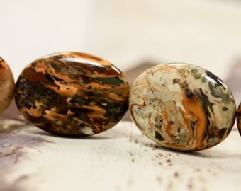 May include: A strand of oval-shaped, brown, white, and black jasper beads. The beads have a mottled, marbled pattern.