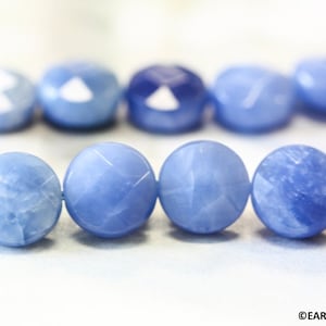 May include: A strand of light blue gemstone beads with a faceted finish. The beads are strung on a thin wire and are arranged in a row.