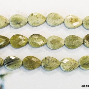 May include: A strand of light green serpentine gemstone beads in a pear shape. The beads have a faceted finish and are strung on a clear thread.