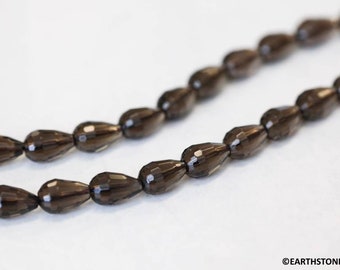 May include: A strand of dark brown faceted teardrop-shaped beads. The beads are strung on a clear thread.
