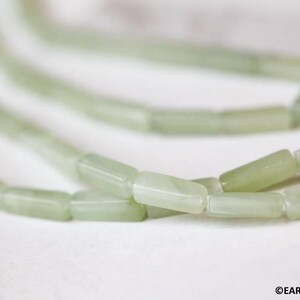 May include: A strand of light green jade beads, each bead is rectangular in shape.