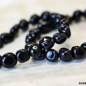 May include: Two black onyx gemstone bracelets with smooth, rounded beads. The bracelets are made of natural black onyx stones.