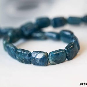 May include: A blue apatite gemstone bracelet with rectangular beads. The bracelet is made of natural stones and is a beautiful piece of jewelry.