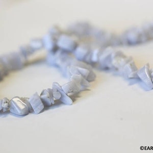 May include: A strand of light blue gemstone beads, with some beads in a circular shape, and others in a more irregular shape.