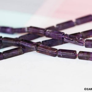 May include: A strand of purple amethyst beads, each bead is a rectangular prism shape.