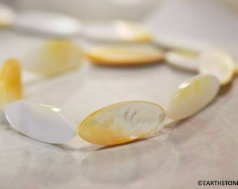 May include: A strand of oval-shaped, iridescent white and yellow shell beads. The beads are strung together to create a necklace or bracelet.