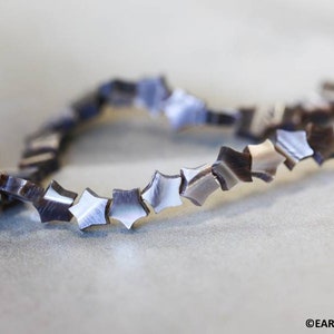 May include: A strand of black and white star-shaped beads made from mother of pearl.