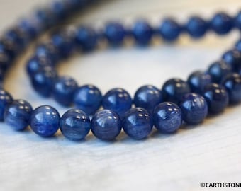 May include: A strand of blue kyanite beads. The beads are round and have a smooth, polished finish. The beads are strung on a clear thread.