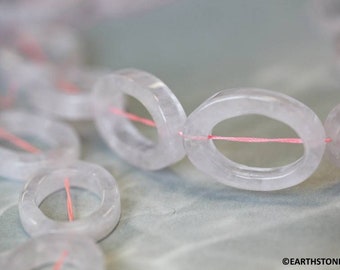 May include: A strand of light pink oval-shaped beads strung together with pink thread. The beads are translucent and have a slightly cloudy appearance.