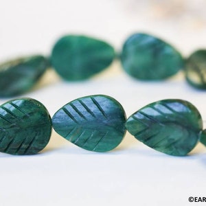 May include: A strand of dark green jade leaf-shaped beads. The beads are carved with a leaf vein pattern.