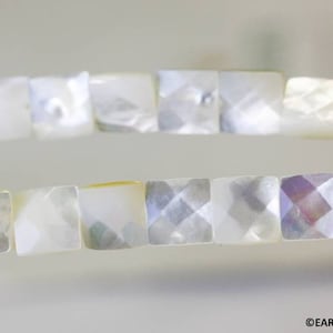 May include: A strand of white iridescent square-shaped beads made from mother of pearl.