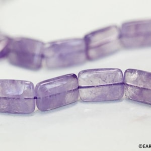 May include: A strand of light purple amethyst beads, each bead is rectangular and faceted. The beads are strung on a clear thread.