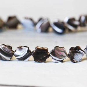 May include: A strand of black and white shell beads in a flower shape.