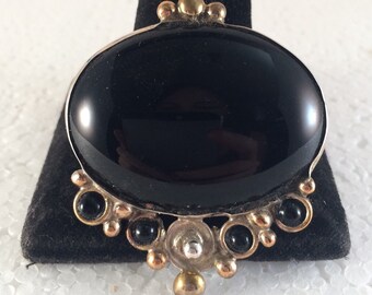 Sterling silver oval pendant/pin with large black onyx stone and surrounding black onyx stones.