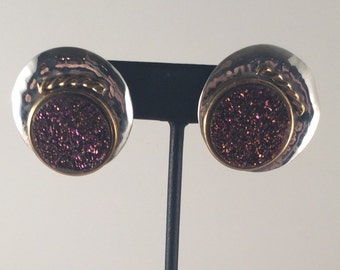 Sterling silver stud earrings with purple/red druzy and brass accents.