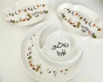 May include: White ceramic serving dishes in cloud and crescent moon shapes. Each dish is decorated with colorful illustrations and Arabic text. The set includes three pieces, perfect for serving appetizers or desserts.