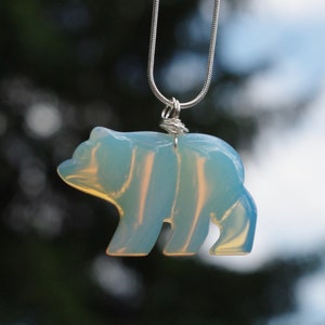 May include: A silver chain necklace with a light blue opal bear pendant.