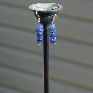 May include: A pair of silver earrings with blue glass beads stacked on each earring.