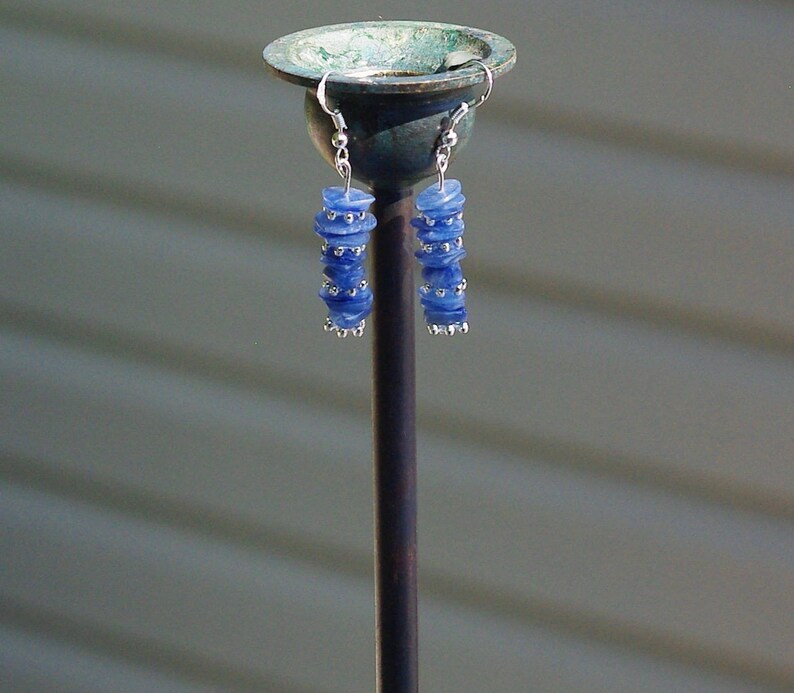 May include: A pair of silver earrings with blue glass beads stacked on each earring.