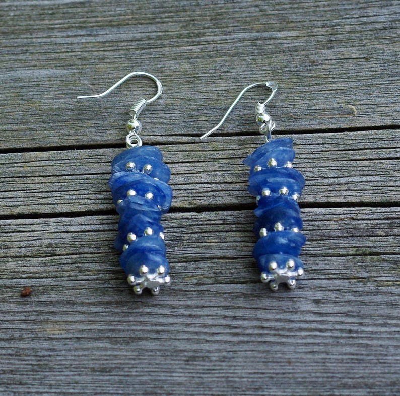 May include: A pair of silver earrings with blue gemstone beads. The beads are stacked in a graduated pattern, with the largest bead at the bottom.