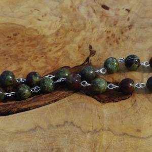 May include: A green, red, and black gemstone necklace with silver chain and clasp.