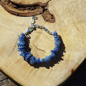 Op de afbeelding: Een blauwe kyanite-stenen armband met zilveren kettingschakels en een sluiting. De armband is gemaakt van natuurlijke stenen en is een prachtig sieraad.