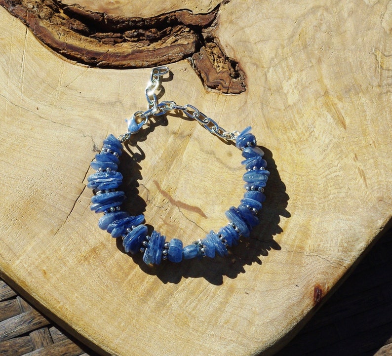 Op de afbeelding: Een blauwe kyanite-stenen armband met zilveren kettingschakels en een sluiting. De armband is gemaakt van natuurlijke stenen en is een prachtig sieraad.