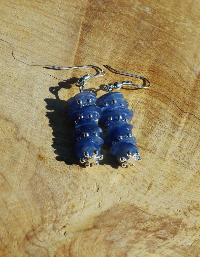 May include: A pair of dangle earrings with a stack of blue gemstone beads and silver accents.