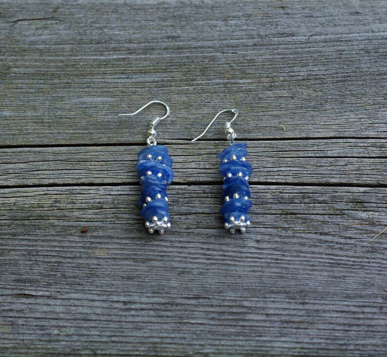 May include: A pair of silver earrings with blue gemstone beads. The beads are stacked and have a faceted, irregular shape.