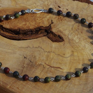 May include: A necklace made with green and red jasper beads and silver chain.