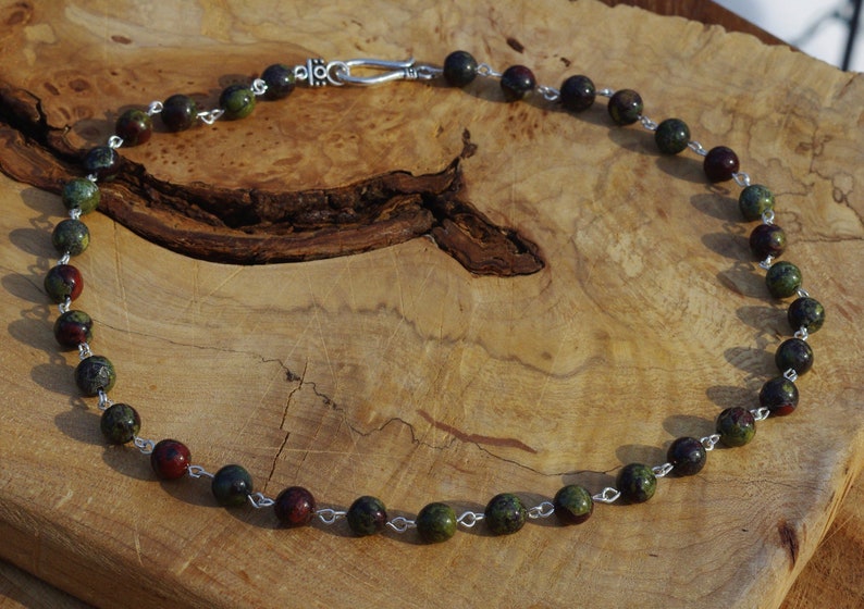 May include: A necklace made with green and red jasper beads and silver chain.