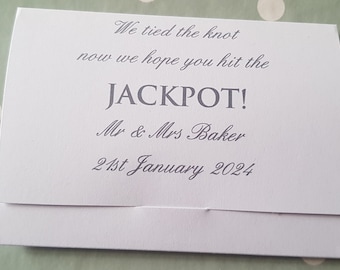 Puede incluir: Tarjeta blanca con el texto "We tied the knot now we hope you hit the JACKPOT! Mr & Mrs Baker 21st January 2024" impreso en gris.