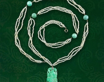 May include: A multi-strand pearl necklace with a carved jade pendant and turquoise beads. The necklace is composed of multiple strands of small, white pearls. The pendant is a carved, light green jade with floral details. The necklace is displayed on a green background.