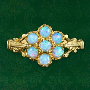 Puede incluir: Un anillo de oro con un diseño floral con siete ópalos blancos.