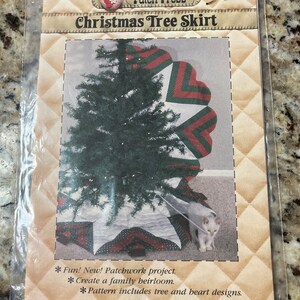 May include: A Christmas tree skirt sewing pattern from Patch Press. The pattern features a red, green, and white patchwork design with a star in the center. The pattern includes instructions for creating a tree and heart design.