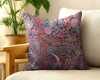 May include: A square throw pillow featuring a dark charcoal background covered in a dense, intricate pattern of concentric circles, small dots, and stylized leaf-like shapes in vibrant shades of magenta, purple, teal, orange, and white.