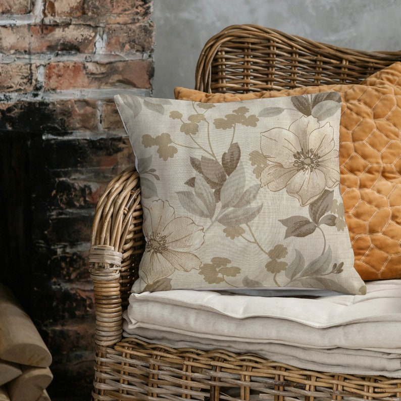 May include: A wicker chair with a beige floral patterned throw pillow and a mustard yellow throw pillow. The chair is in front of a brick fireplace.