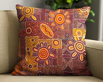 May include: A square throw pillow featuring a vibrant pattern of stylized suns and geometric shapes in shades of deep red, orange, yellow, and brown. The design incorporates intricate dot work and repeating motifs across the entire fabric surface.